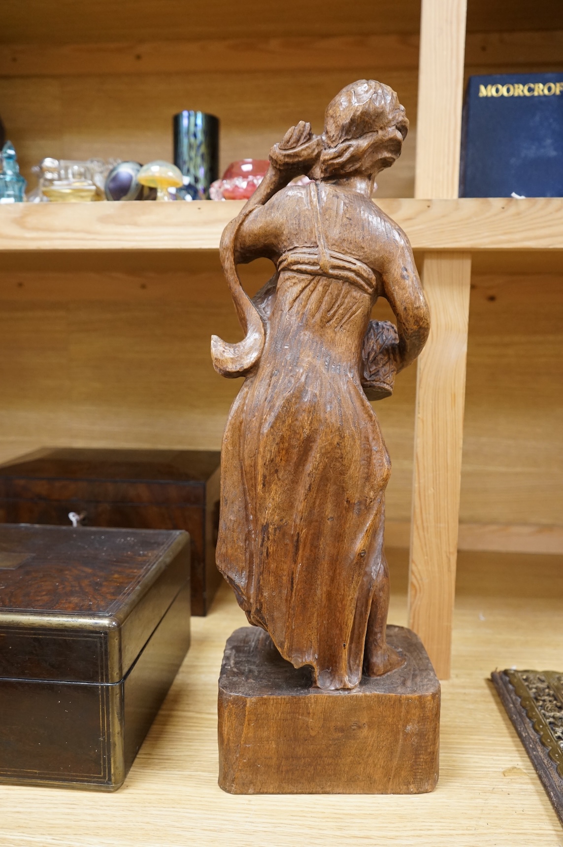 A carved walnut figure of a girl holding a basket of flowers, 54cm high
